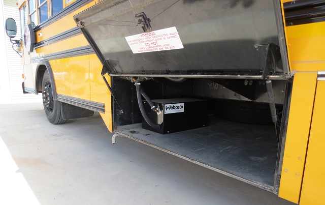 A fuel operated engine heater is installed in the luggage compartment of this school bus.