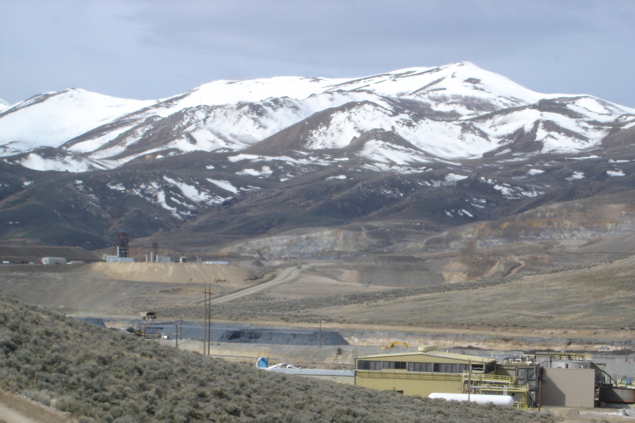 Snow covered mountains behind a mining operation.